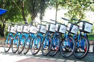 Estación de bicicletas gratuitas Encicla en Medellín Colombia con algunas bicicletas estacionadas frente a un parque.
