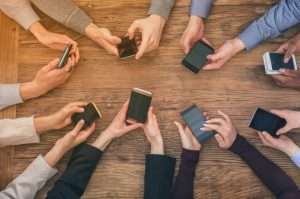 Alto ángulo de visión de las manos de empresarios utilizando teléfonos móviles en una mesa de madera