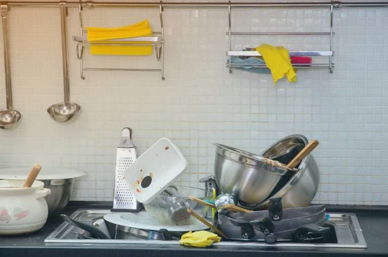 Cocina sucia con muchos platos y utensilios sucios en el fregadero, uno de los mayores problemas en una vivienda compartida.