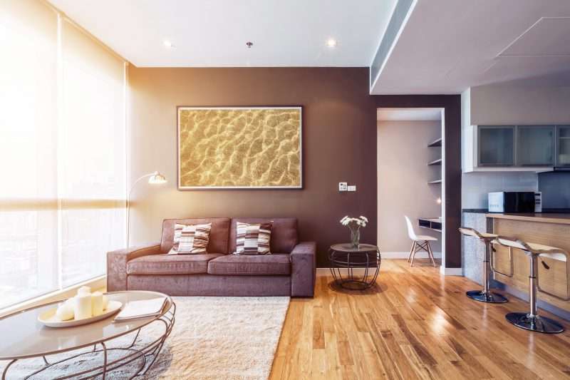 Interior moderno y hermoso de una sala de estar con una gran ventana que permite que la luz ilumine todo el salón durante la puesta de sol.
