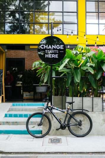 Indie Studio coliving building in Laureles Medellin, "change starts here" sign with a bike. Creative community VICO rent a room in Medellin